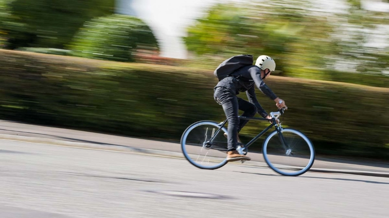 Ein Radfahrer mit Helm fährt schnell eine Straße herunter Ein Radfahrer mit Helm fährt schnell eine Straße herunter